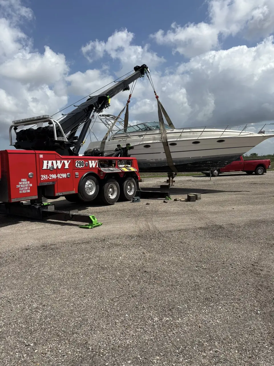 HWY 290 Wrecker using its boom to lift a cabin cruiser boat onto blocks