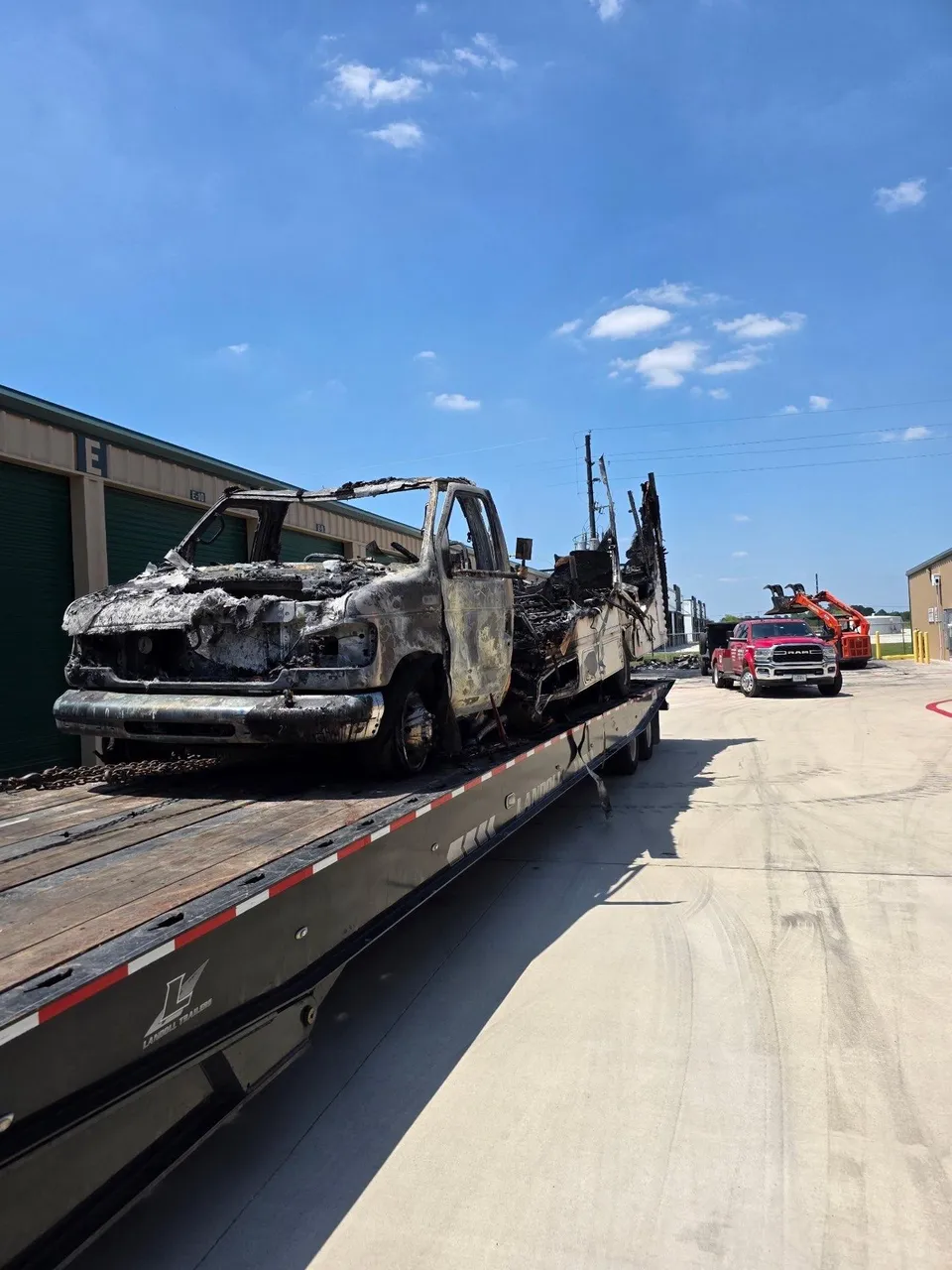 Fire-damaged box truck loaded on a Landoll trailer for transport