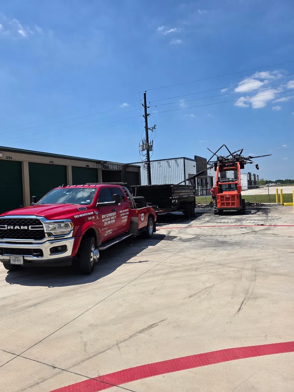 HWY 290 Wrecker truck with a dump trailer and skid steer at a commercial job site