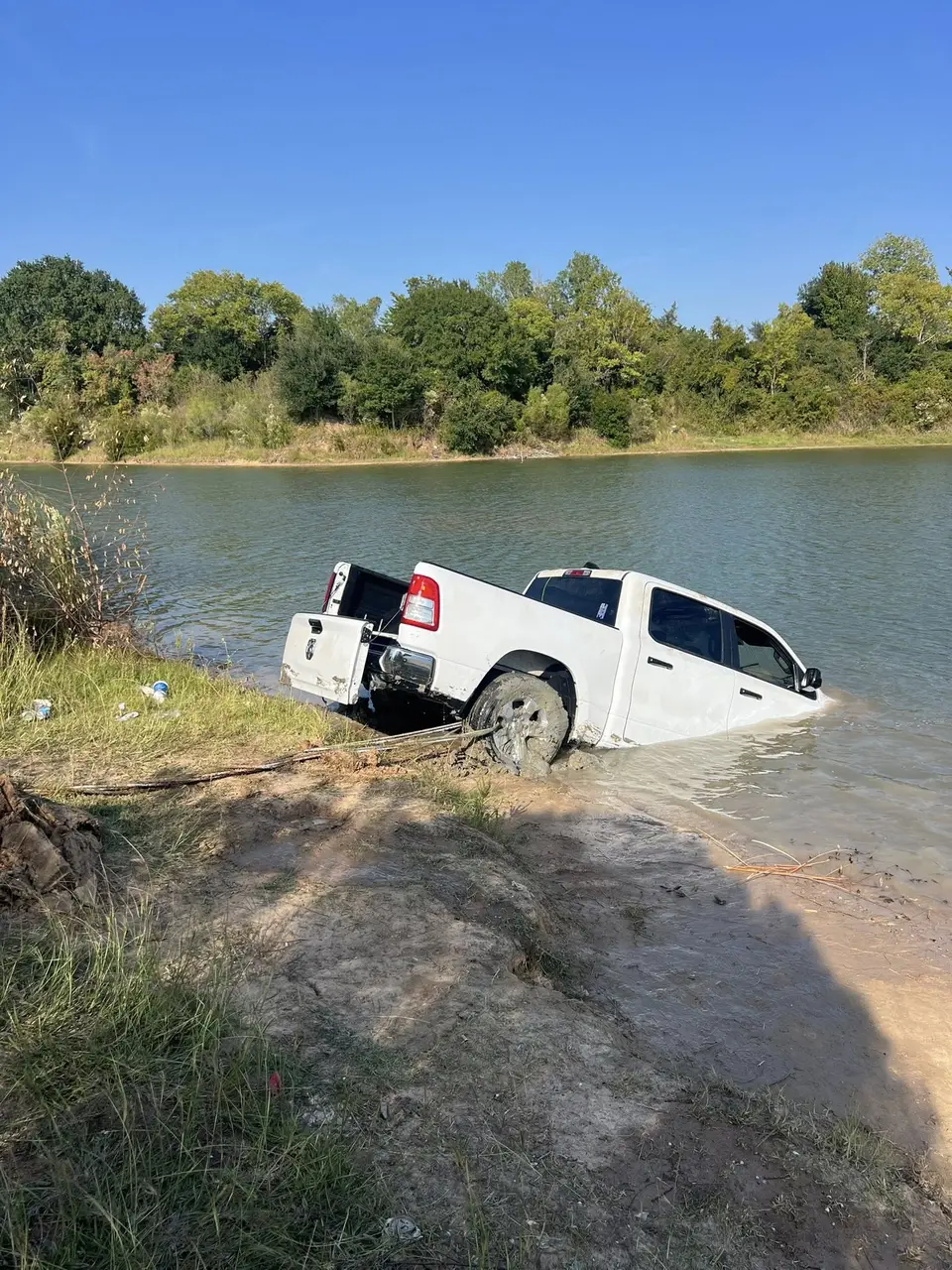 White pickup truck half-submerged in a pond being winched out by HWY 290 Wrecker