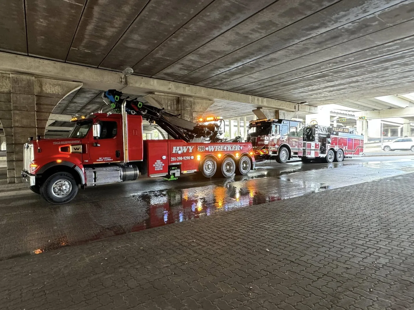 Two HWY 290 Wrecker heavy-duty tow trucks staged under a Houston overpass at night