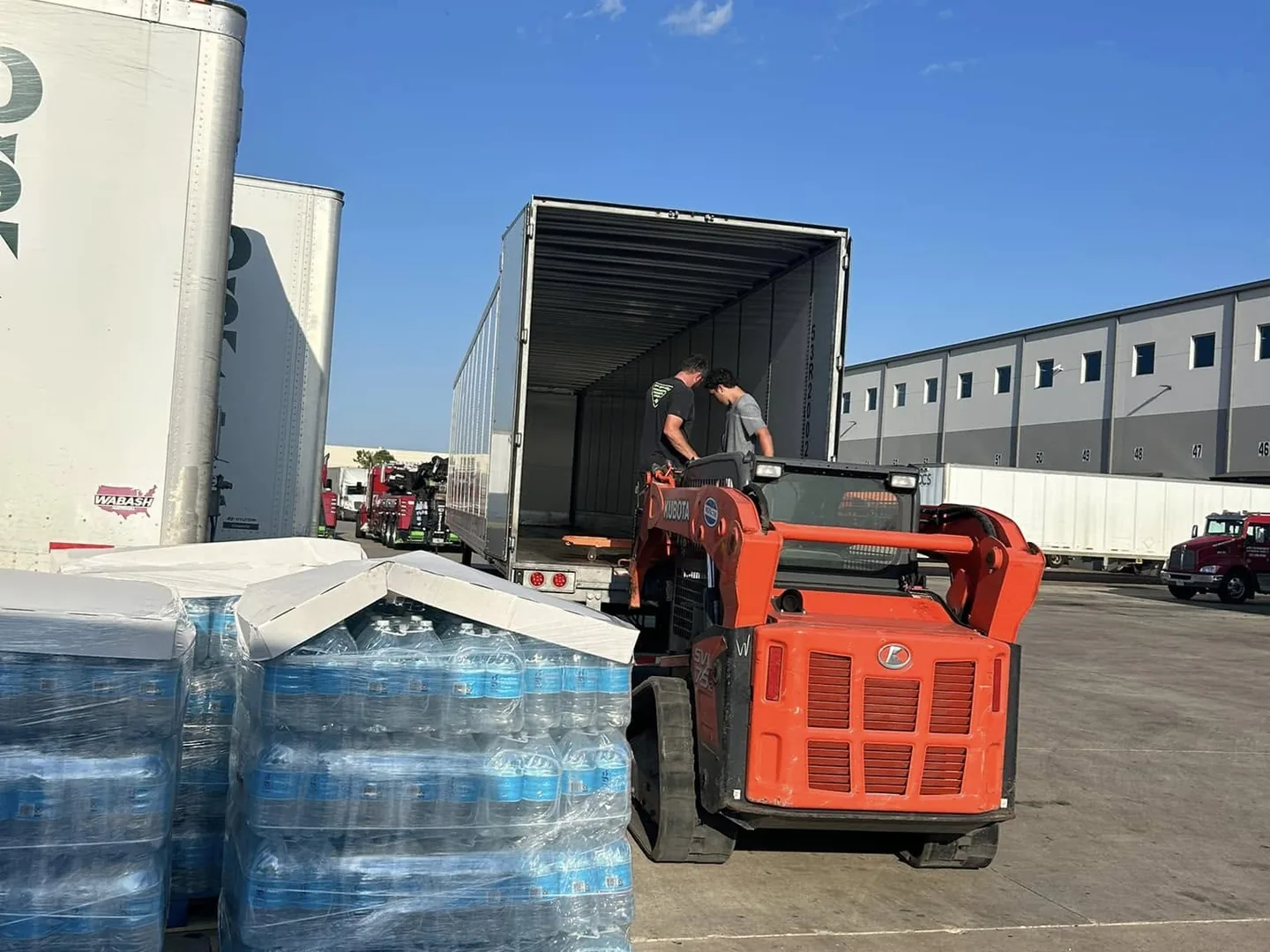 Skid steer transferring palletized freight into a trailer for a load swap